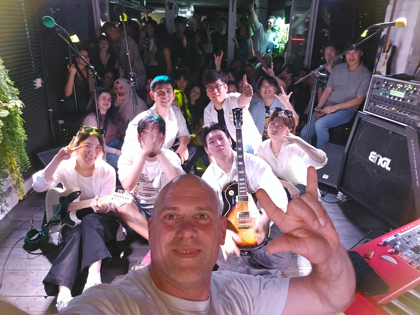 Gemeinsames Gruppenfoto mit Gitarren und Publikum auf der Bühne
