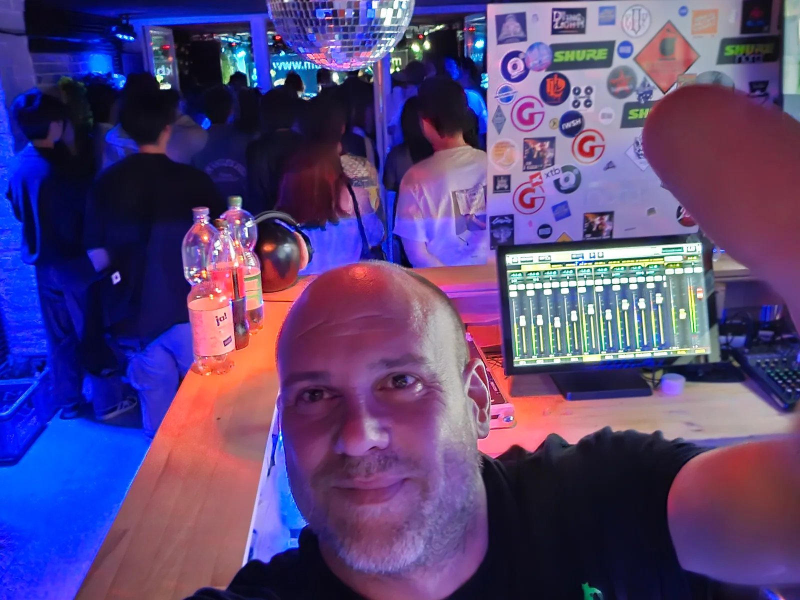 Selfie am digitalen Mischpult mit Publikum im Hintergrund